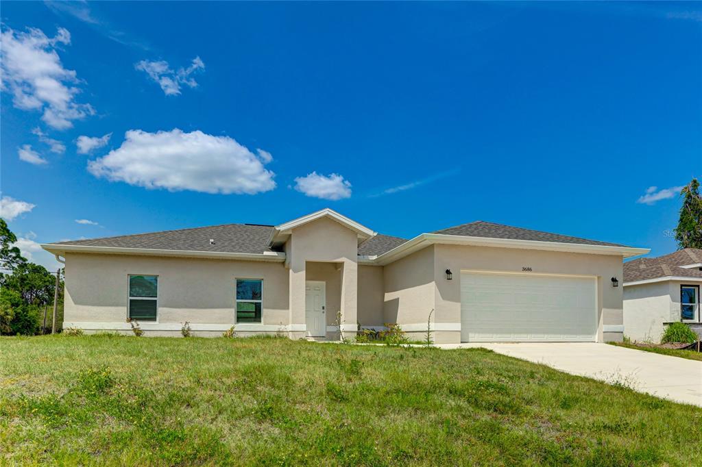 A single-story beige house with a two-car garage and a front-facing entrance under a gable — 3686 LUBEC AVENUE, NORTH PORT, FL