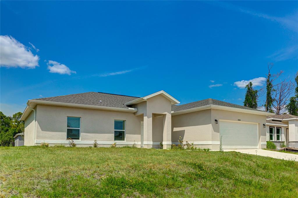 A single-story house with a beige stucco exterior, a two-car garage, and a grassy lawn — 3686 LUBEC AVENUE, NORTH PORT, FL
