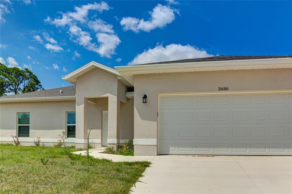 A single-story house with a beige stucco exterior, a two-car garage, and a covered entryway — 3686 LUBEC AVENUE, NORTH PORT, FL