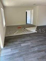 An interior room features gray wood-look flooring and a raised platform with unfinished subflooring — 3199 DELTONA BOULEVARD, SPRING HILL, FL