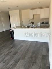 A kitchen with white cabinets and a breakfast bar overlooks a room with wood flooring — 3199 DELTONA BOULEVARD, SPRING HILL, FL