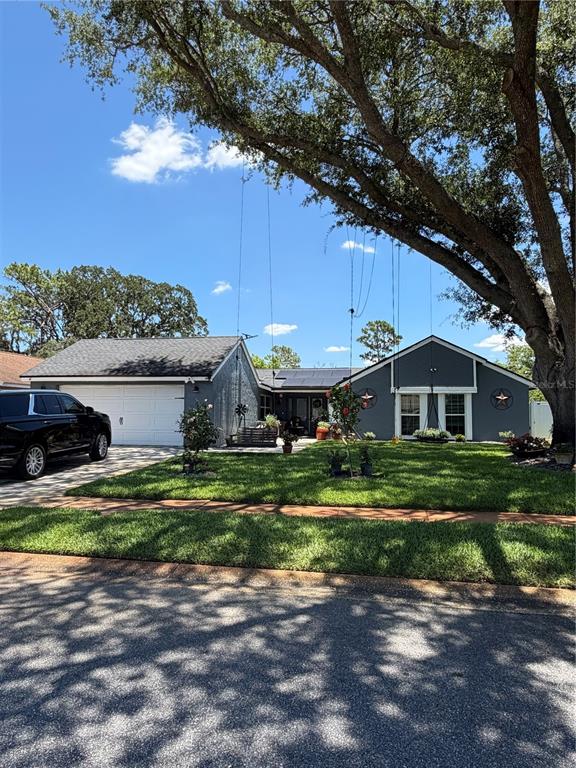A gray single-story house with a two-car garage sits behind a large tree — 1409 PONCE DE LEON BOULEVARD, WINTER SPRINGS, FL
