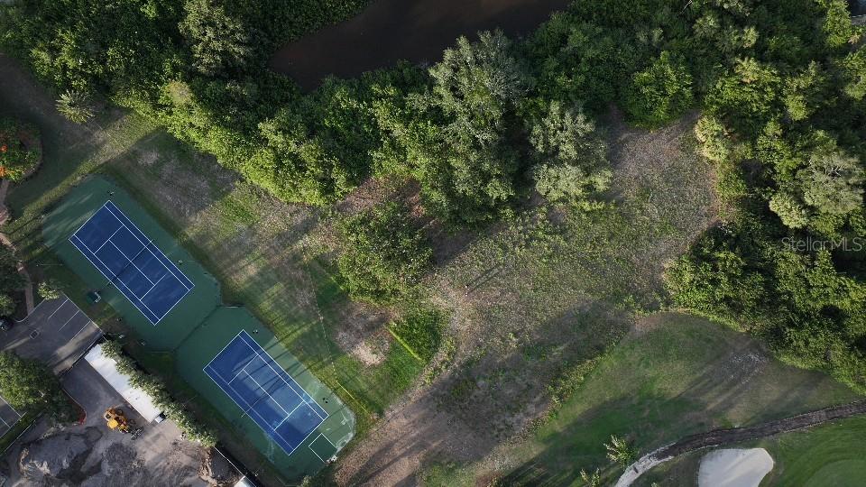 An aerial view shows two tennis courts adjacent to a wooded area and a golf course — 6064 PASADENA POINT BOULEVARD S, GULFPORT, FL