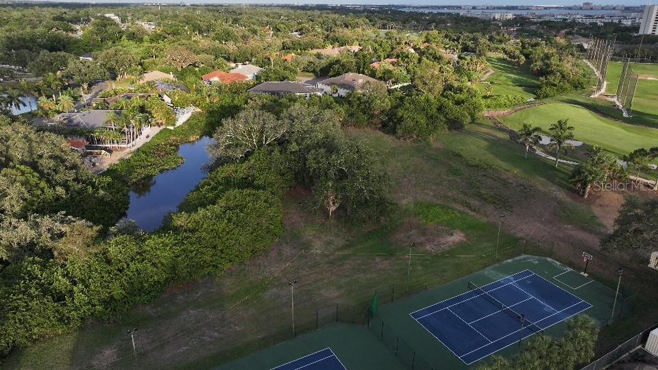 An aerial view shows tennis courts next to a pond and a golf course — 6064 PASADENA POINT BOULEVARD S, GULFPORT, FL