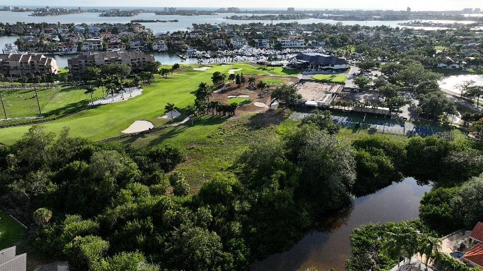 An aerial view shows a golf course, a pond, and residential buildings near the water — 6064 PASADENA POINT BOULEVARD S, GULFPORT, FL