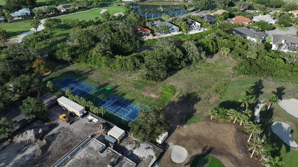 An aerial view shows two tennis courts adjacent to a construction site and golf course — 6064 PASADENA POINT BOULEVARD S, GULFPORT, FL