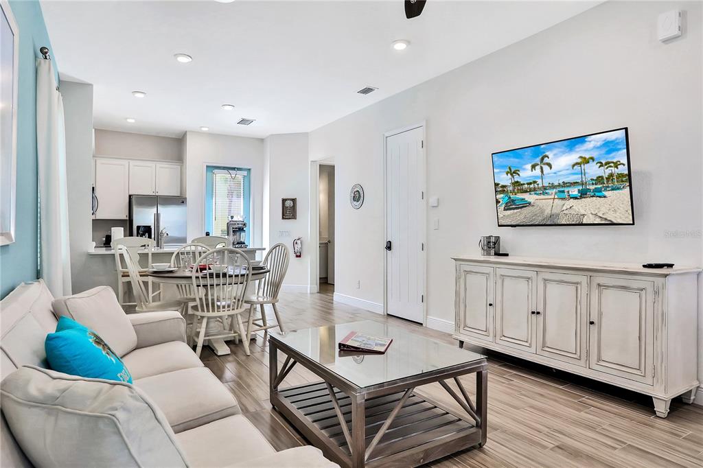 A living room with a beige sofa, glass coffee table, and a wall-mounted television — 8038 SURF STREET, KISSIMMEE, FL