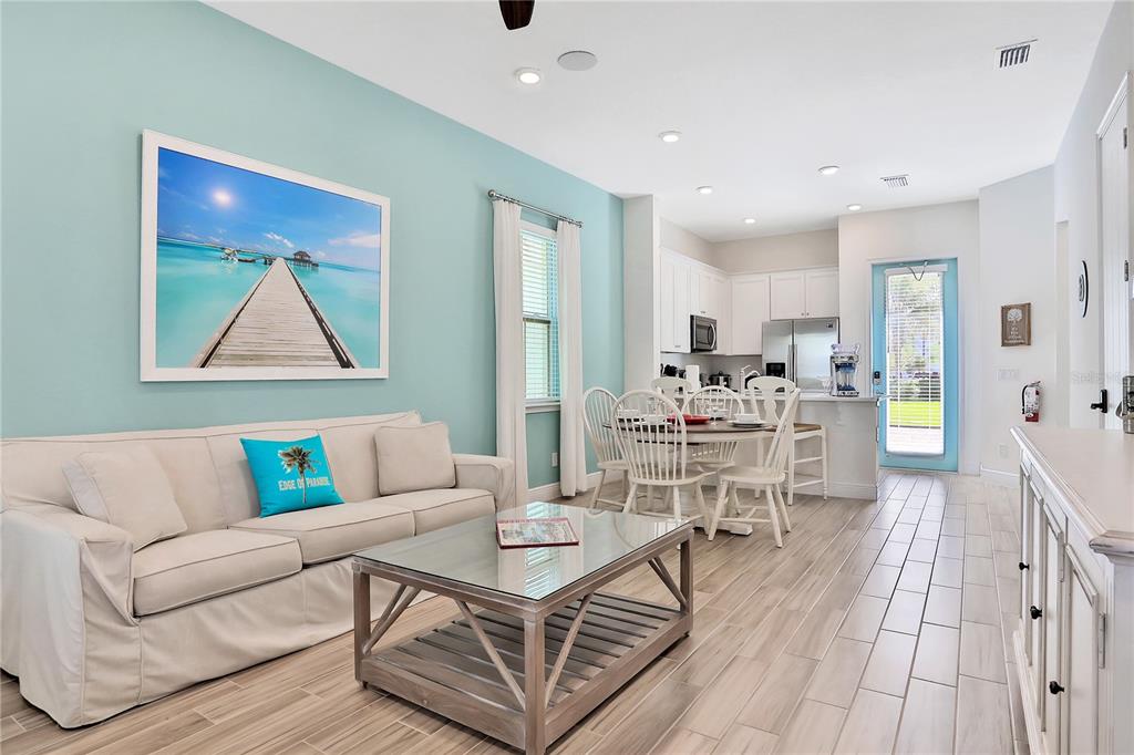 A living room and dining area feature light blue walls, wood-look tile floors, and white cabinetry — 8038 SURF STREET, KISSIMMEE, FL