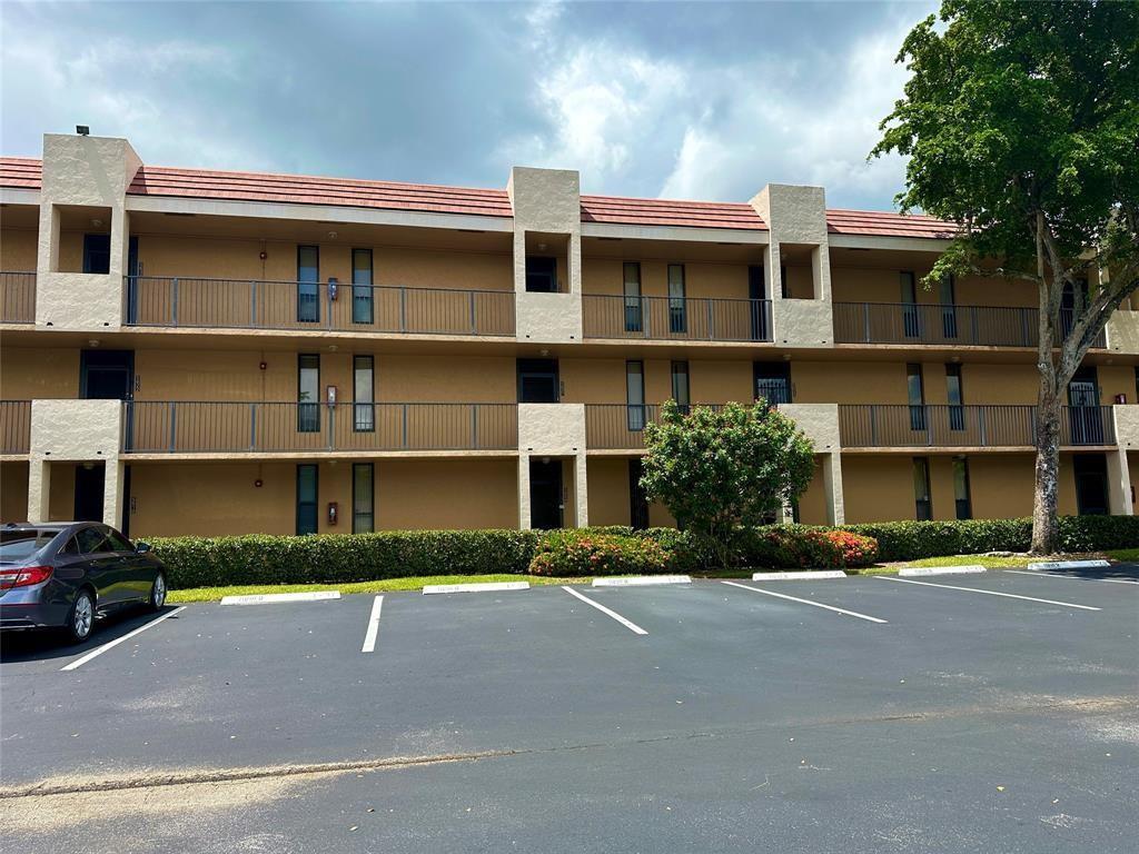 A three-story apartment building with a tan exterior, metal railings, and a parking lot — 5609 Coral Lake # 109, Margate FL 33063, MARGATE, FL