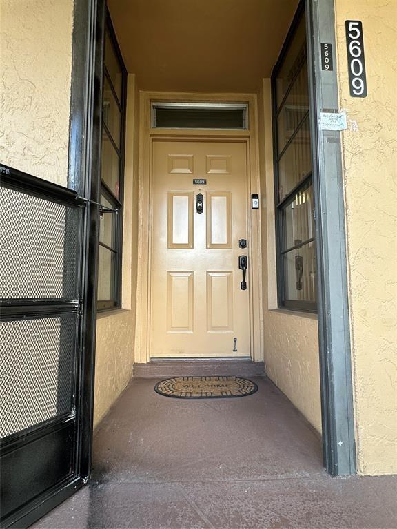 A tan front door with a transom window is framed by side windows and a screen — 5609 Coral Lake # 109, Margate FL 33063, MARGATE, FL