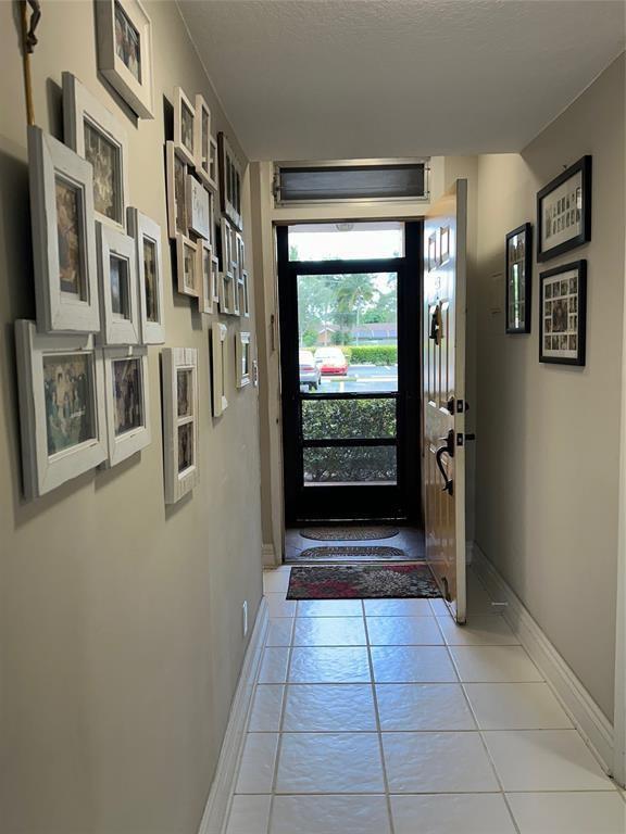 A tiled entryway features a gallery wall of framed photos and an open front door — 5609 Coral Lake # 109, Margate FL 33063, MARGATE, FL