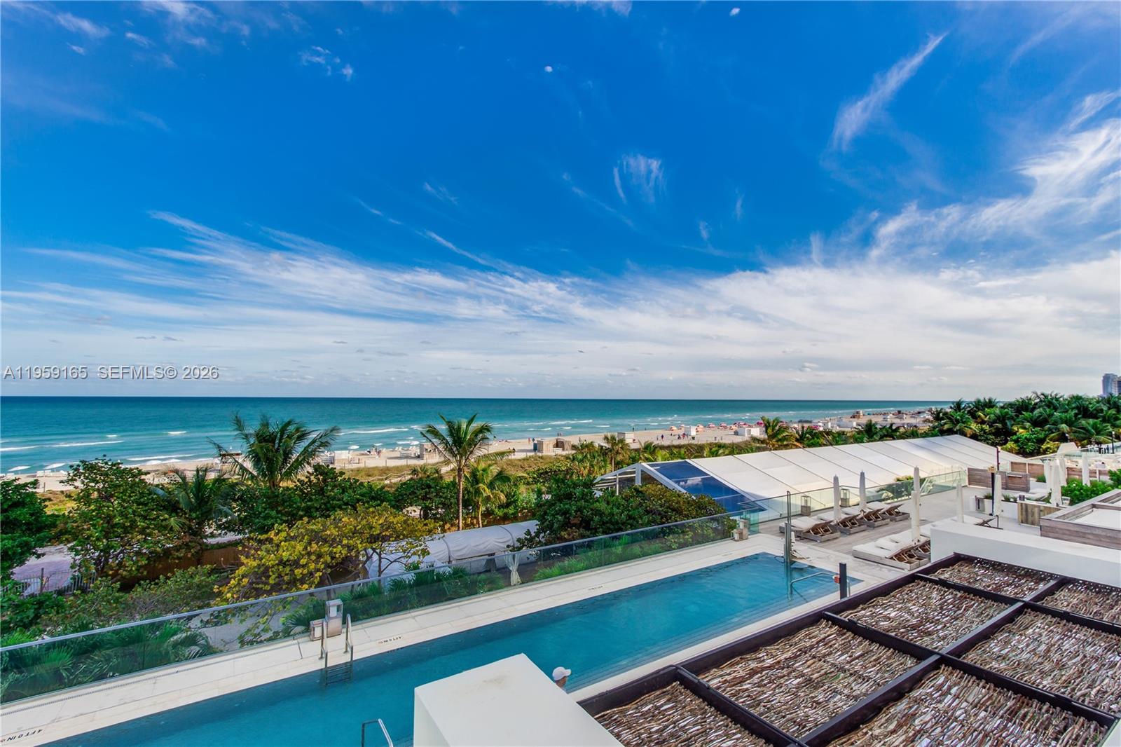 A living room features a beige sofa, a natural wood coffee table, and a wicker chair — 102 24th St # 1007, Miami Beach FL 33139, MIAMI BEACH, FL