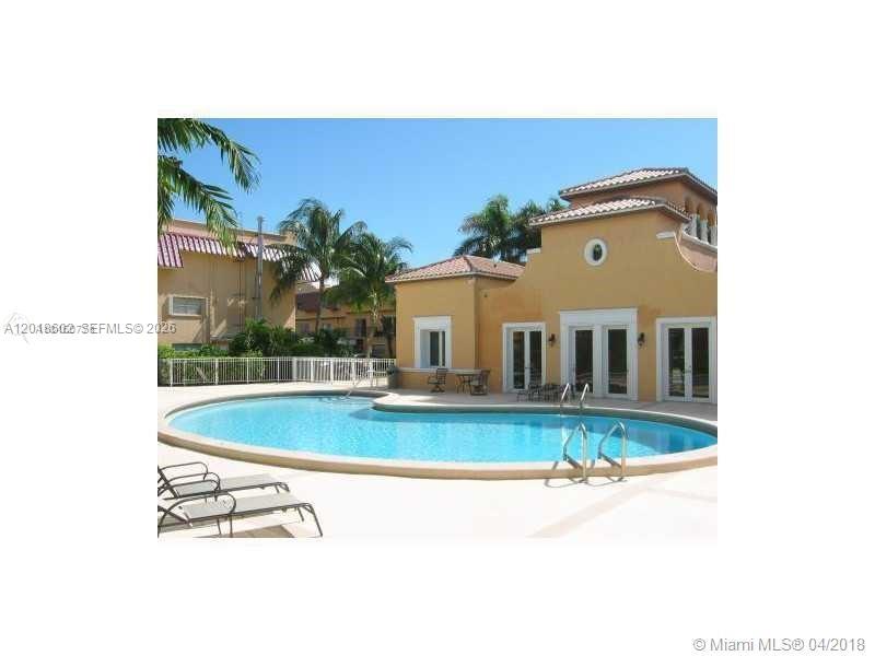 A swimming pool sits in front of a tan building with a tiled roof — 6713 N Kendall Dr # 611, Pinecrest FL 33156, PINECREST, FL