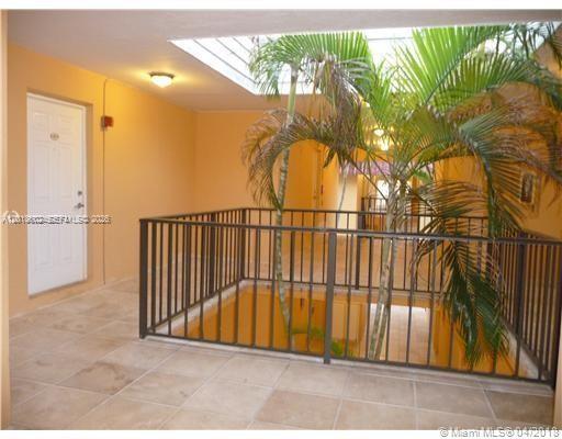 An indoor atrium hallway features a metal railing, a skylight, and a potted palm tree — 6713 N Kendall Dr # 611, Pinecrest FL 33156, PINECREST, FL