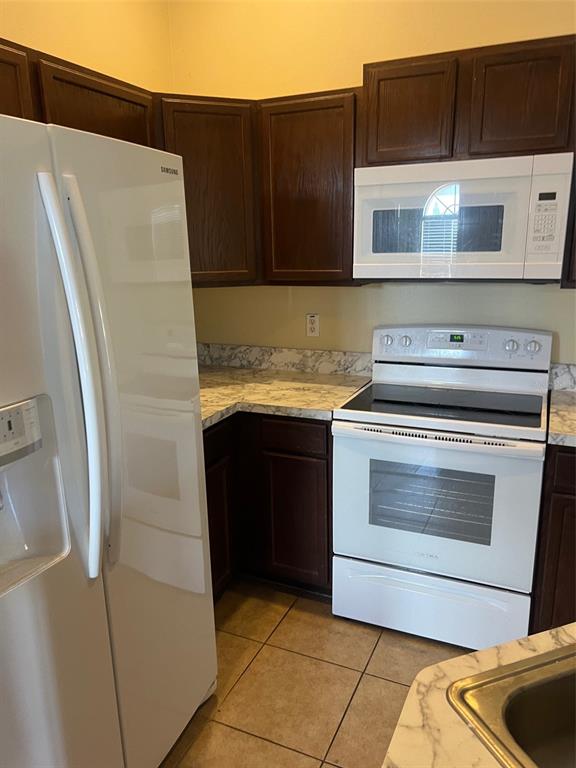 A kitchen features dark wood cabinets, white appliances, and a marble-patterned laminate countertop — 9122 MOONLIT MEADOWS LOOP UNIT 1, RIVERVIEW, FL
