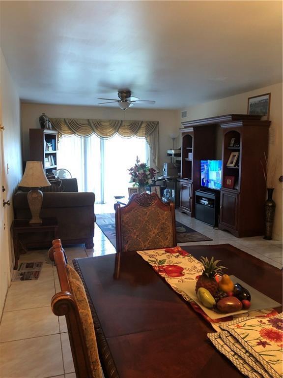 A dining area in the foreground opens into a living room with a ceiling fan — LAUDERHILL, FL