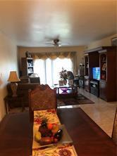 A living room with tile flooring, a ceiling fan, and a large wooden entertainment center — LAUDERHILL, FL