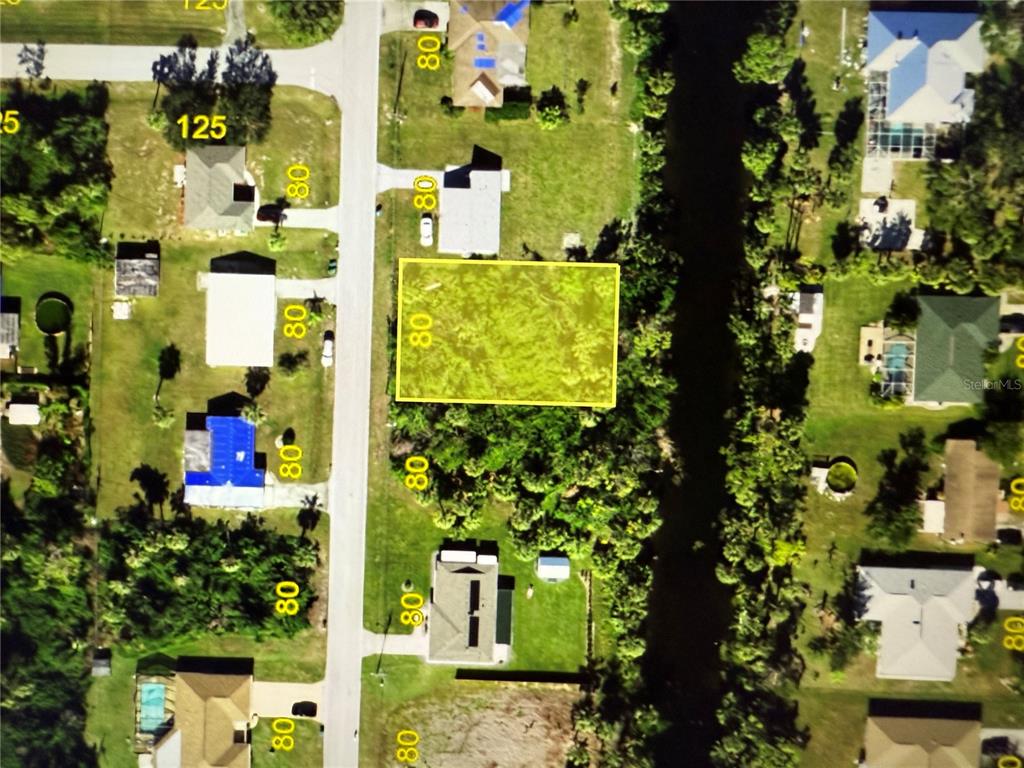 An aerial view shows a vacant, rectangular residential lot highlighted in yellow along a street — 1402 YORKSHIRE STREET, PORT CHARLOTTE, FL