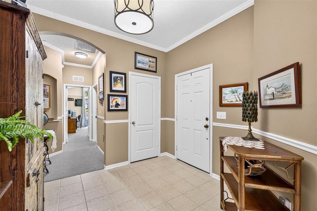An entryway features tile flooring, beige walls with white trim, a white door, and a hallway — 19355 HASKELL PLACE, LAND O LAKES, FL