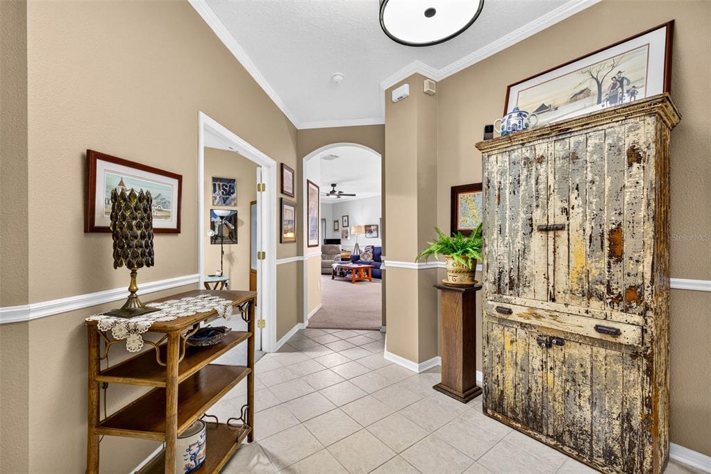 A tiled entryway features a rustic wooden cabinet, a side table, and an arched doorway — 19355 HASKELL PLACE, LAND O LAKES, FL