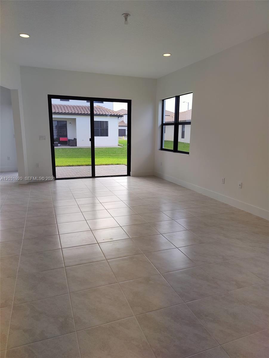 An empty room features light-colored tile flooring, white walls, recessed lighting, and sliding glass doors — 5573 Cobalto Way # 5573, Ave Maria FL 34142, AVE MARIA, FL