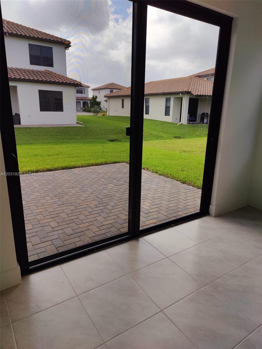 A view from a tiled room through a sliding glass door to a paved patio — 5573 Cobalto Way # 5573, Ave Maria FL 34142, AVE MARIA, FL