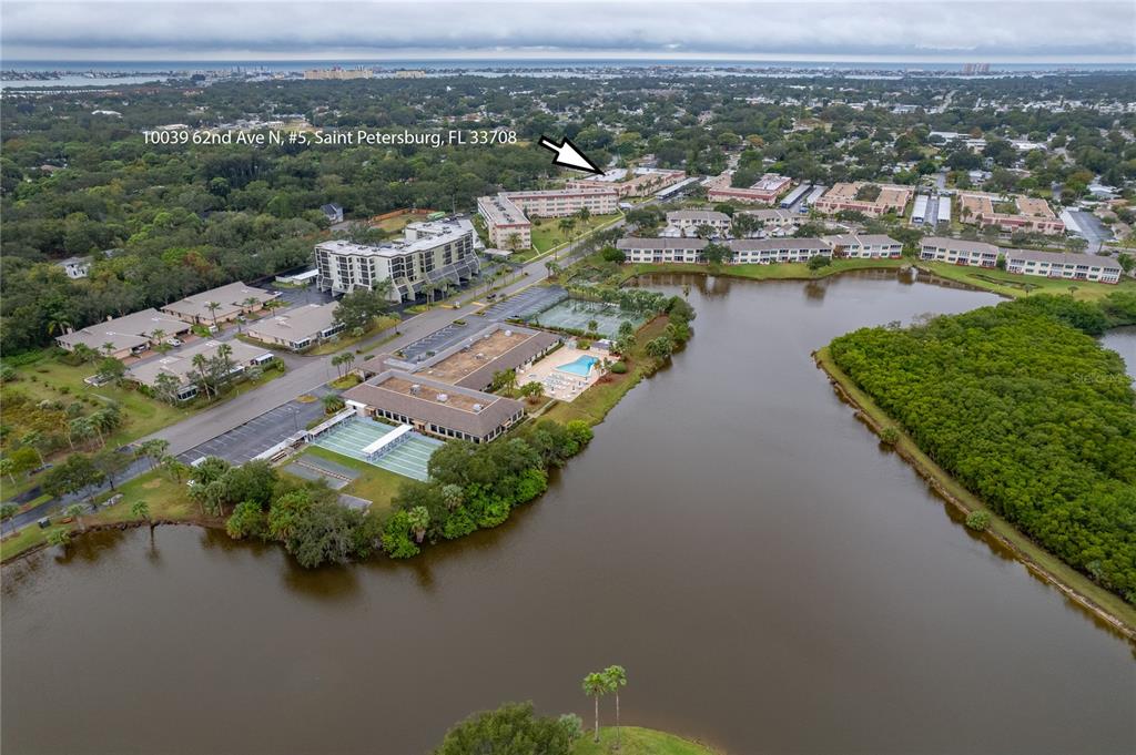An aerial view shows a multi-building residential complex situated next to a large lake — 10032 65TH AVENUE N UNIT 17, ST PETERSBURG, FL