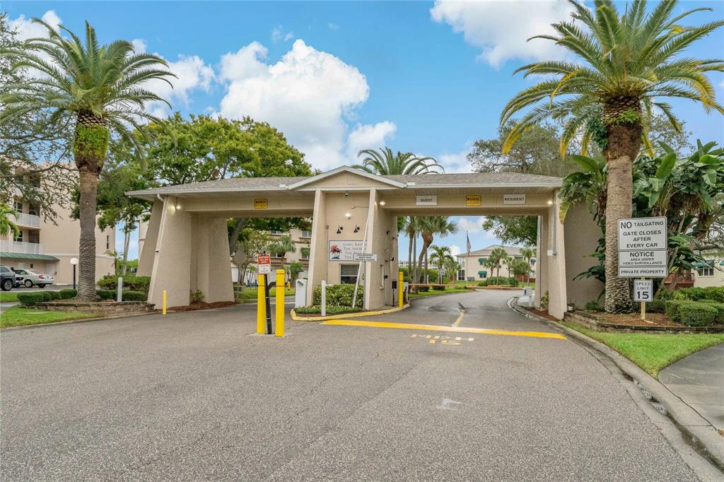 A gated entrance to a residential community features palm trees and a speed limit sign — 10032 65TH AVENUE N UNIT 17, ST PETERSBURG, FL