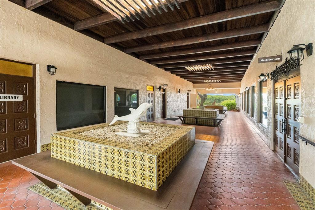 An outdoor covered walkway features tiled fountains with dolphin sculptures and a terracotta floor — 10032 65TH AVENUE N UNIT 17, ST PETERSBURG, FL