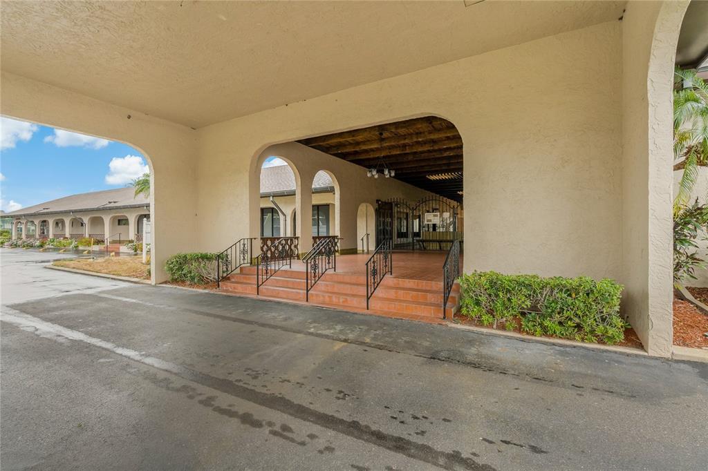 A covered building entrance features a paved driveway, arched openings, and a set of stairs — 10032 65TH AVENUE N UNIT 17, ST PETERSBURG, FL
