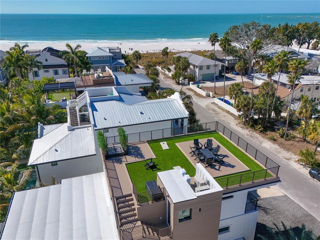 An aerial view shows a rooftop deck with artificial turf, dining furniture, and ocean views — 111 PALMETTO AVENUE, ANNA MARIA, FL