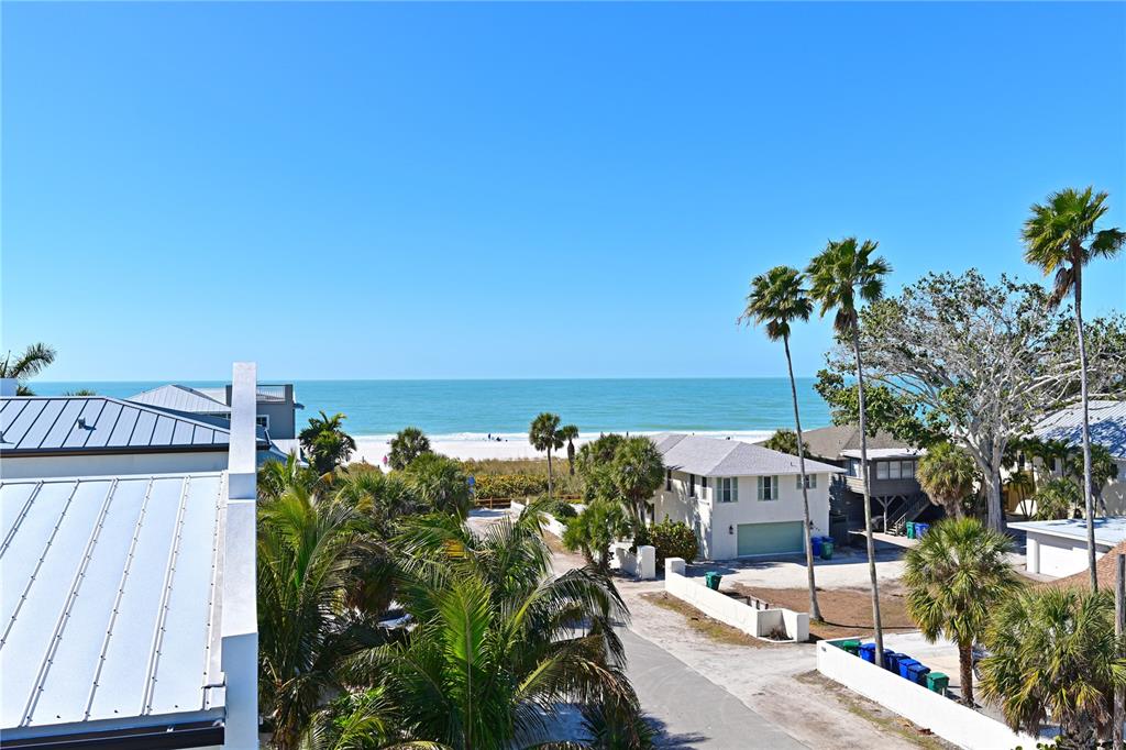 An elevated view of a beach, palm trees, and coastal houses under a clear sky — 111 PALMETTO AVENUE, ANNA MARIA, FL