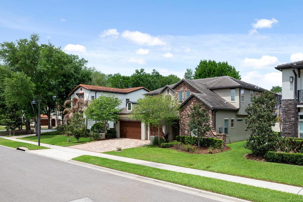 A stone-accented home entrance features double dark wood doors, a lantern, and potted topiary trees — 706 CANOPY ESTATES DRIVE, WINTER GARDEN, FL