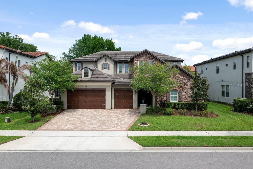 A two-story suburban house with a stone facade, brown garage doors, and a paved driveway — 706 CANOPY ESTATES DRIVE, WINTER GARDEN, FL