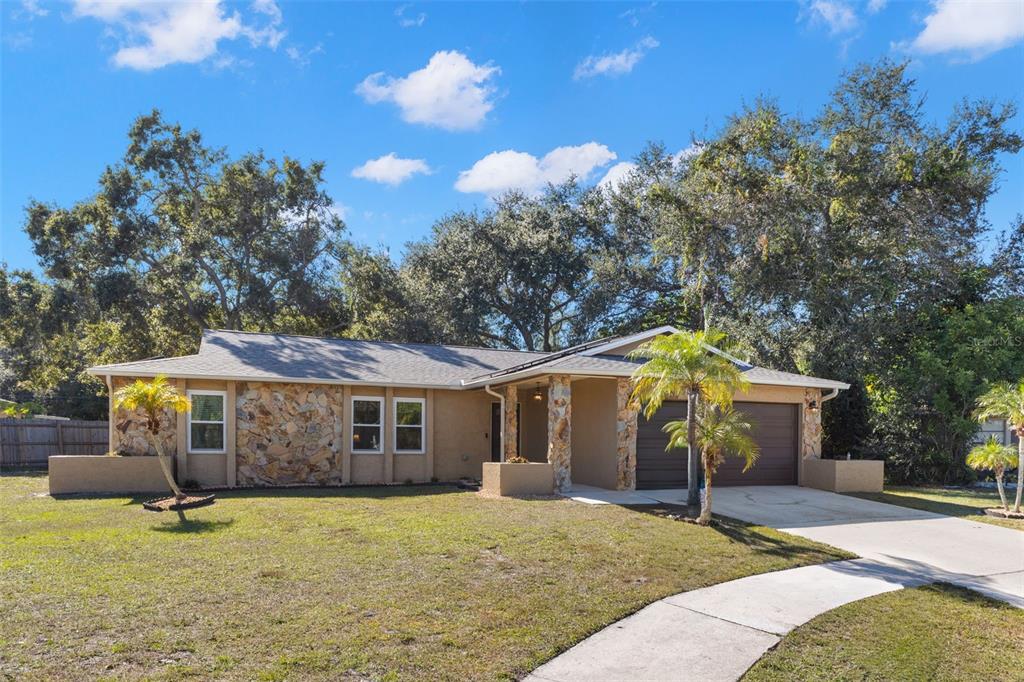 A single-story house with a stone facade, a two-car garage, and a front lawn — 112 MEADOWCROSS DRIVE, SAFETY HARBOR, FL