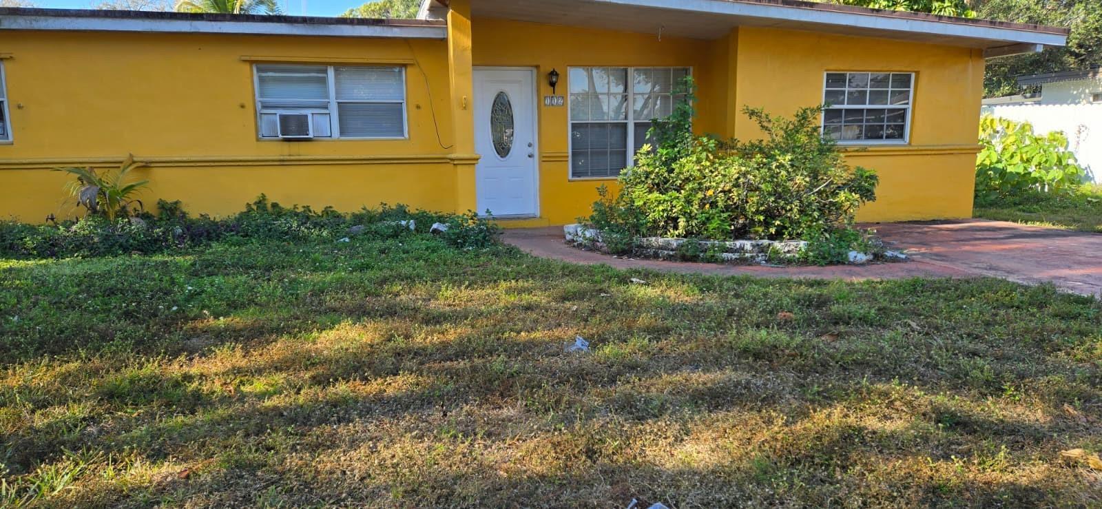 A single-story yellow house with a white front door and a front yard — 112 Newton Road, West Park FL 33023, WEST PARK, FL