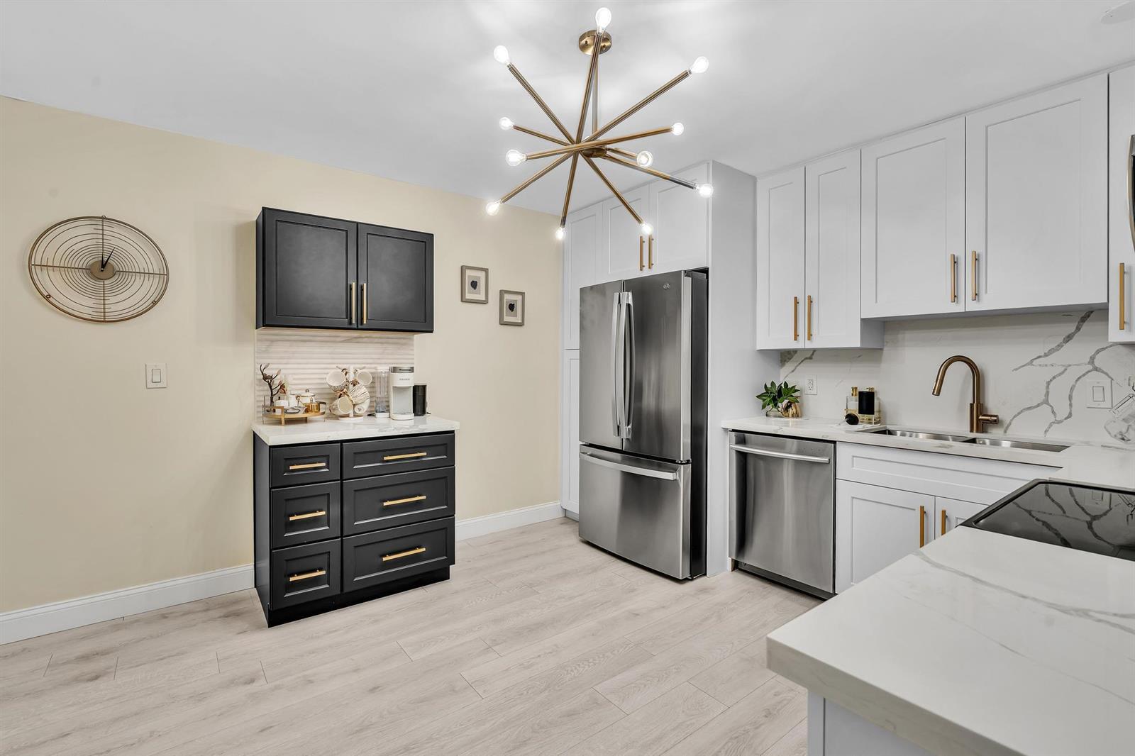 A kitchen features white and black cabinetry, stainless steel appliances, and a modern sputnik chandelier — 2804 N 46th Avenue # C330, Hollywood FL 33021, HOLLYWOOD, FL