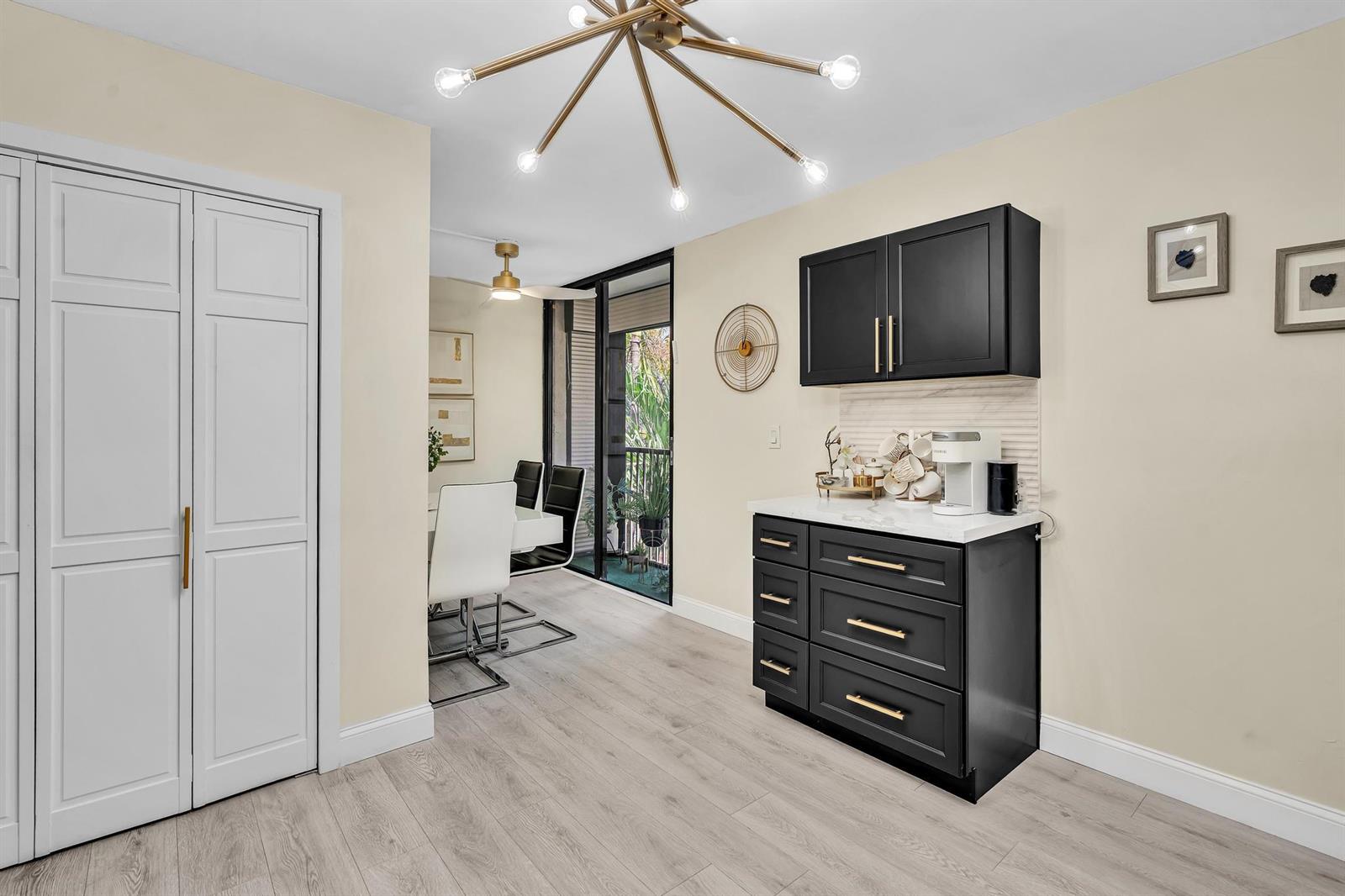 A dining area features a modern chandelier, a black coffee bar, and a balcony view — 2804 N 46th Avenue # C330, Hollywood FL 33021, HOLLYWOOD, FL