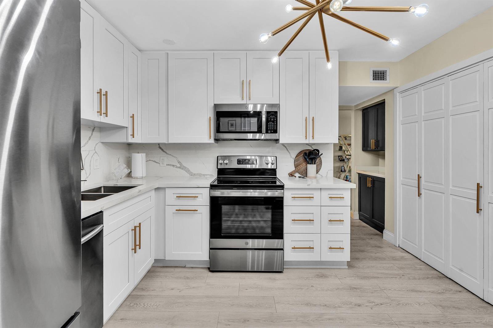 A modern kitchen features white cabinets, stainless steel appliances, gold hardware, and marble-patterned countertops — 2804 N 46th Avenue # C330, Hollywood FL 33021, HOLLYWOOD, FL