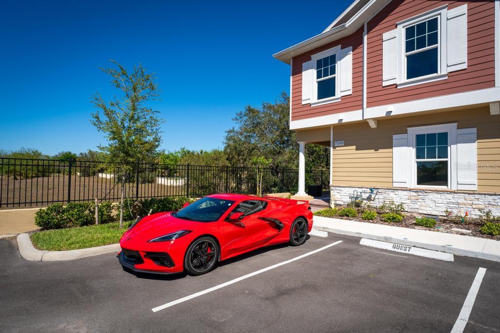 A red sports car is parked in a guest space next to a two-story house — 7549 SUNFLOWER CIRCLE, KISSIMMEE, FL
