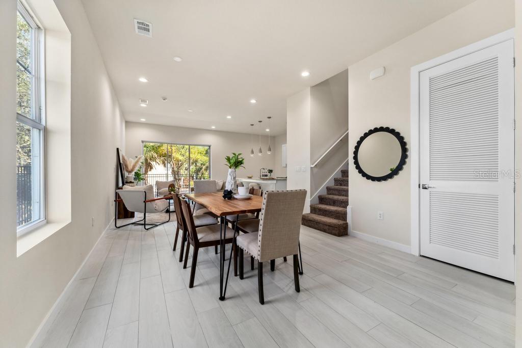 A dining area with a wooden table and chairs sits next to a carpeted staircase — 7549 SUNFLOWER CIRCLE, KISSIMMEE, FL