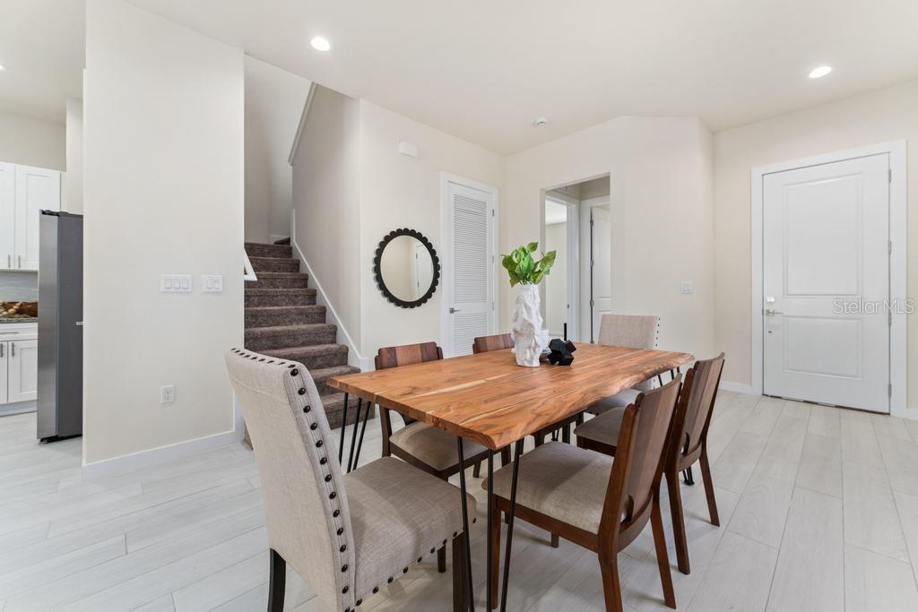 A dining area features a live-edge wood table, upholstered chairs, and stairs with carpet — 7549 SUNFLOWER CIRCLE, KISSIMMEE, FL