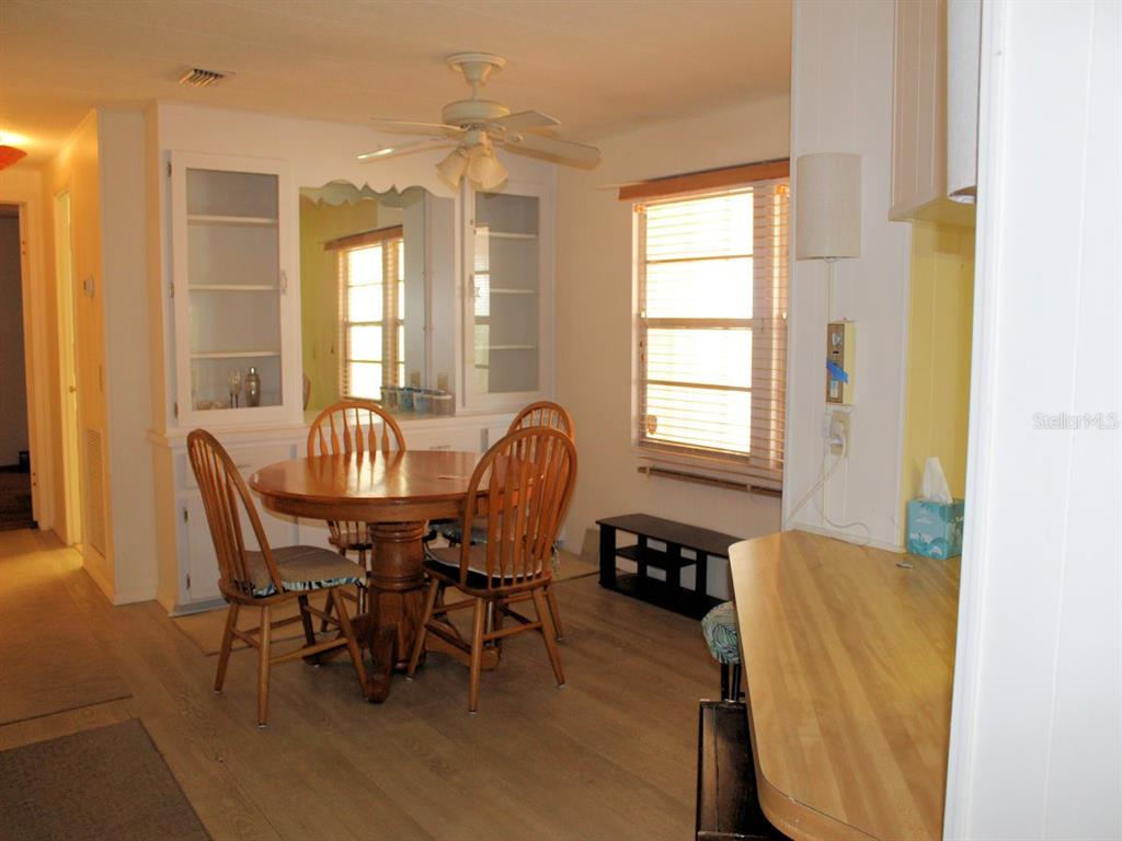 A dining area features a round wooden table, four chairs, a built-in hutch, and windows — 476 NEEDLE PALM STREET, LARGO, FL