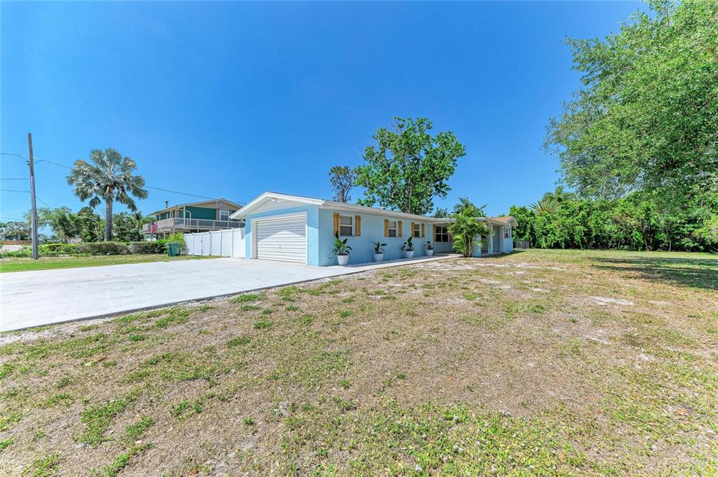 A light blue single-story house with a white garage door and a large concrete driveway — 2401 10TH STREET W, PALMETTO, FL
