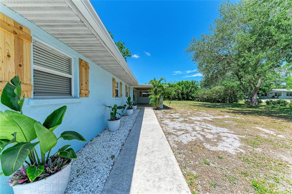 A light blue house exterior features a concrete walkway, white gravel, and potted plants — 2401 10TH STREET W, PALMETTO, FL