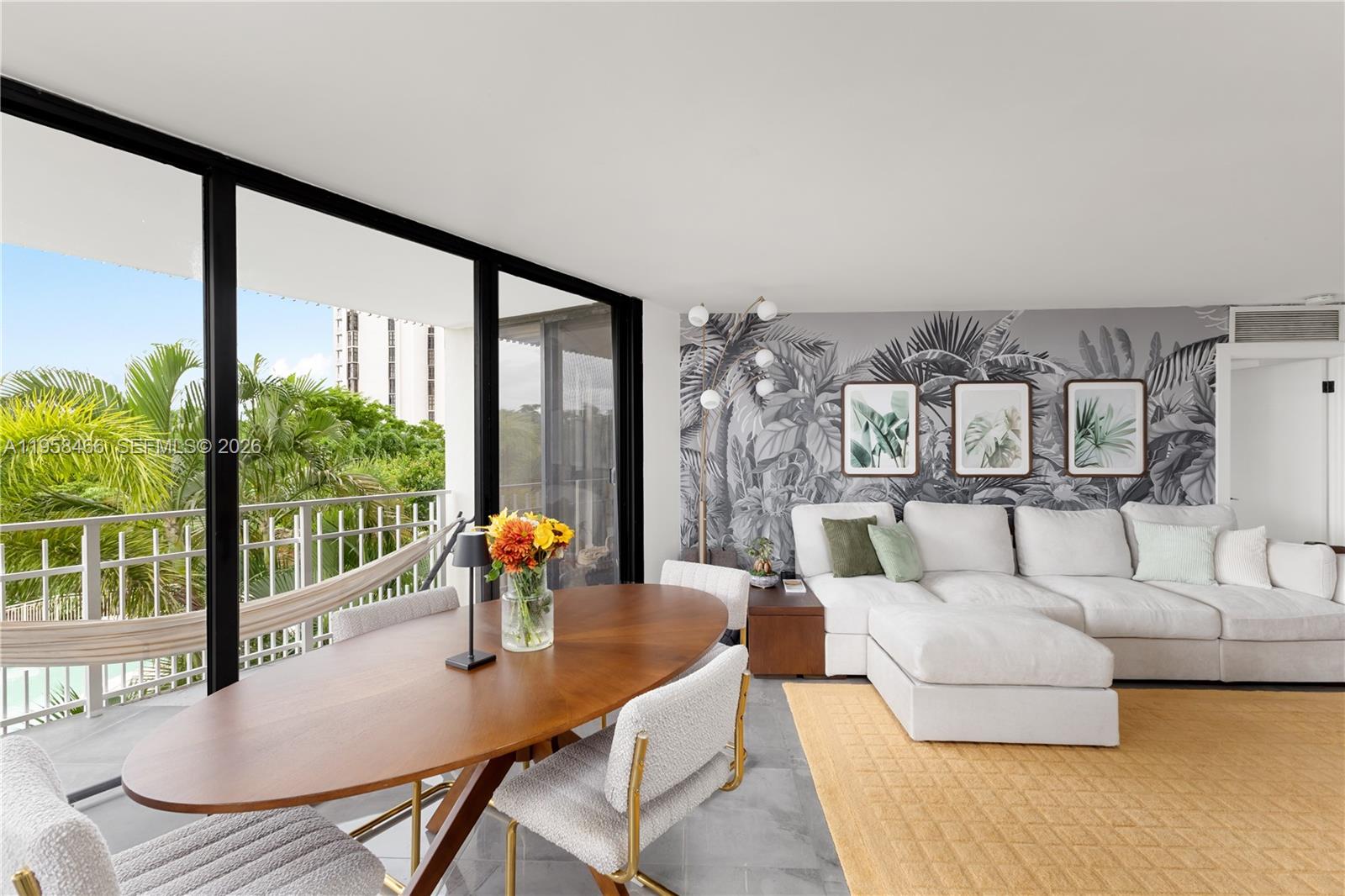 A living and dining area features a tropical mural, white sectional, and floor-to-ceiling windows — 1000 Quayside Ter # 506, Miami FL 33138, MIAMI, FL