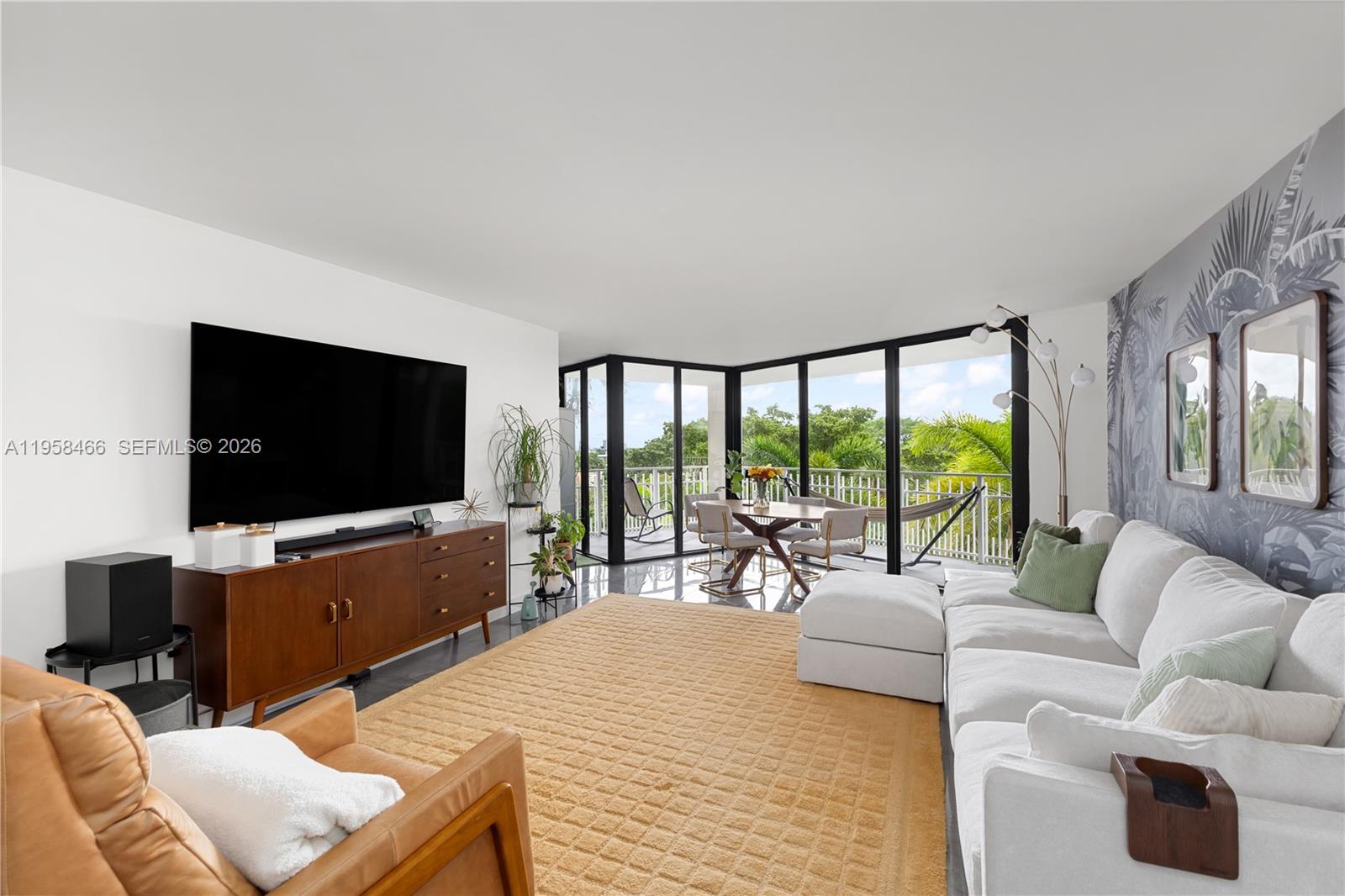 A living room features a large white sectional, a yellow rug, and floor-to-ceiling windows — 1000 Quayside Ter # 506, Miami FL 33138, MIAMI, FL