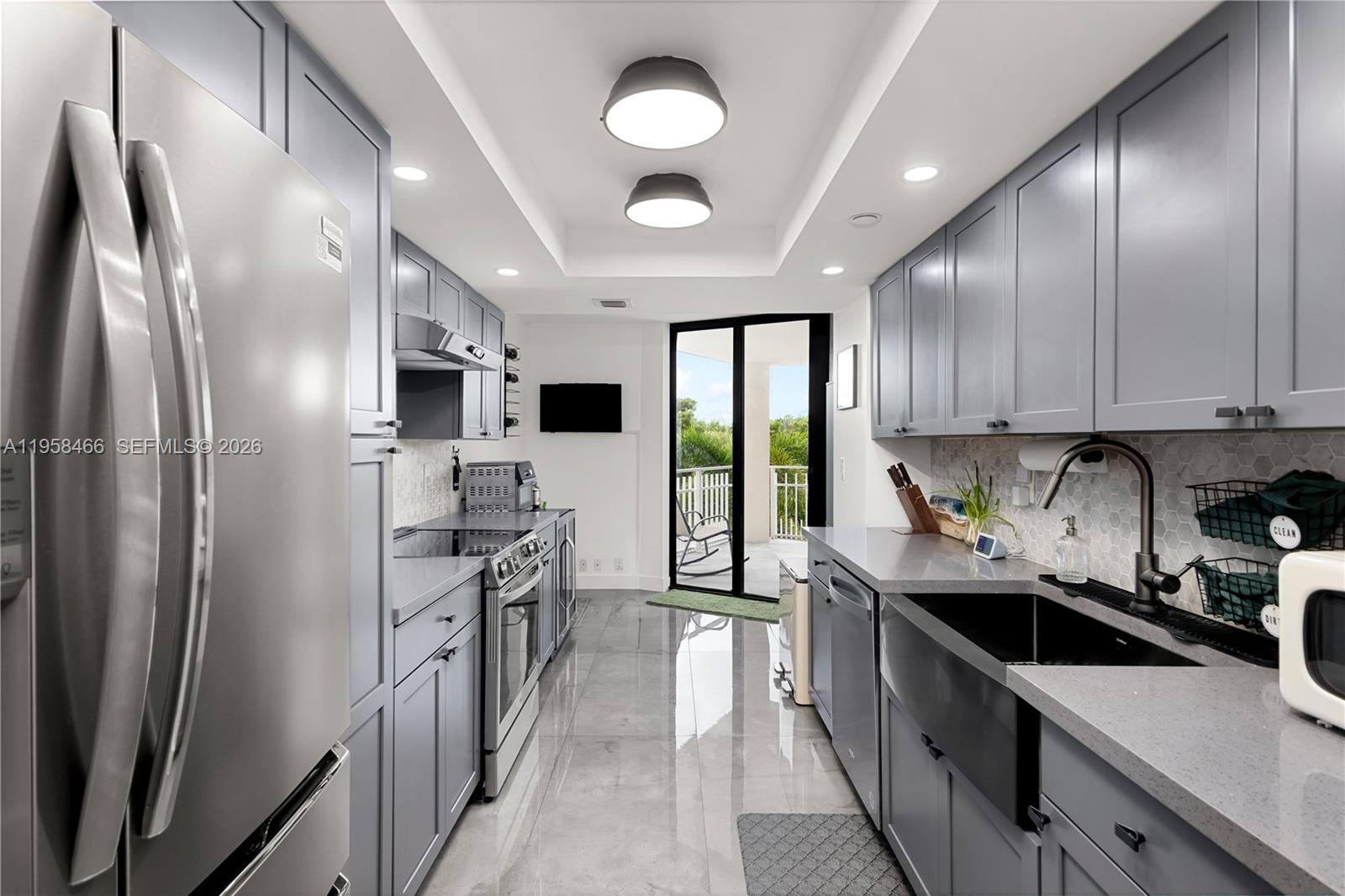 A galley kitchen features gray cabinetry, stainless steel appliances, and a view of a balcony — 1000 Quayside Ter # 506, Miami FL 33138, MIAMI, FL