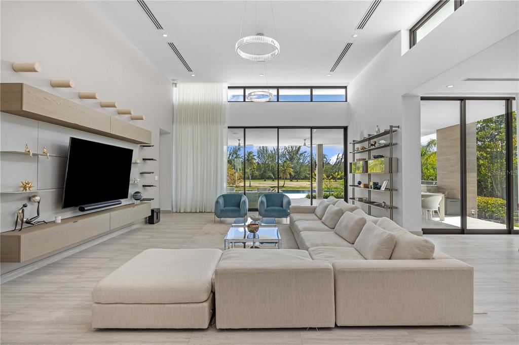 A modern living room features a large sectional sofa, media wall, and floor-to-ceiling windows — 13 SALT LANE, THE ISLES AT DORADO BEACH, DORADO, PR