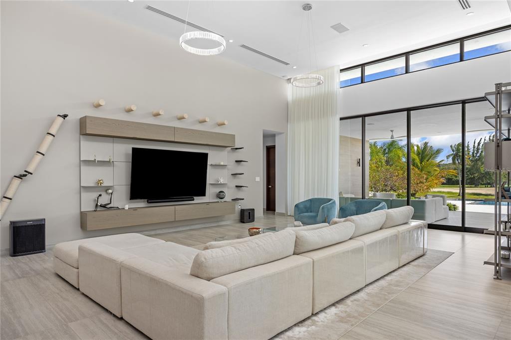 A spacious living room features a large sectional sofa, a wall-mounted television, and floor-to-ceiling windows — 13 SALT LANE, THE ISLES AT DORADO BEACH, DORADO, PR